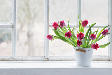 red tulips on old white windowsill
