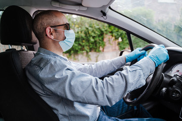 man driving a car wearing protective mask and gloves during pandemic coronacirus covid-19