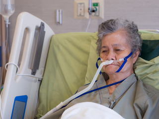 Close-up of elderly woman patient with lung disease, getting oxygen for treatment in the room at...