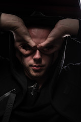 Low key studio portrait of a man in black hoods on a black background make themselves superhero...