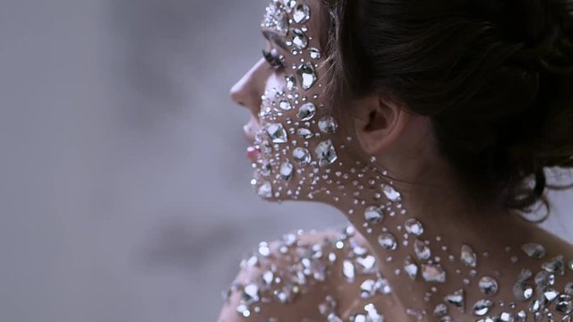 Fantastic fashion portrait of a young beautiful woman with transparent crystals on her face and shoulders. Portrait of a diamond girl, fabulous skin
