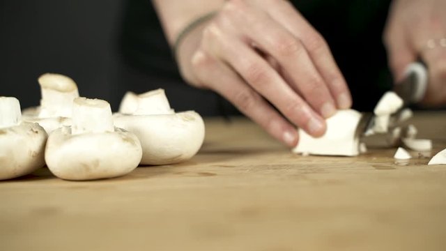 Las manos de una chica trocean unos champi&ntilde;ones sobre una tabla de madera.