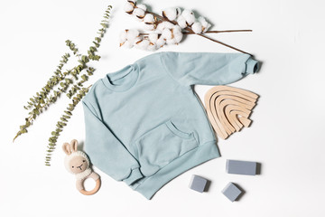 Background of children's products. Concept of clothing for babies. mint t-shirt, a toy, a rattle