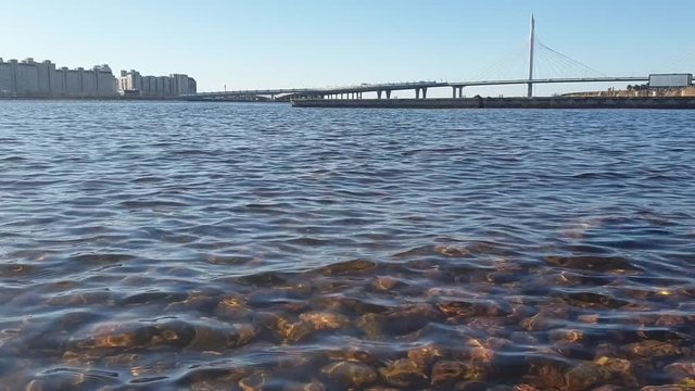 Road bridge over the river. St. Petersburg.Beautiful stones but a bottom under clean water. Finnish gulf of the Baltic Sea. Spring.