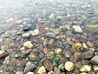 Multicolored smooth and sharp stones in the clear water of lake Baikal.