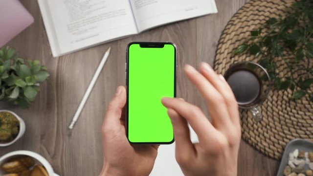Male hands with phone nervously tap many times on green screen on it. Chroma key, nervous, doesn't work. Outrage and stress. Fast tapping. Workspace table on the background. Top view. 4k.