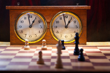 Old wooden vintage chess clock with an endgame on chessboard 