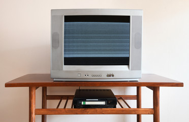 Old silver-colored TV with a VCR on the background of wallpaper.Screen noise.