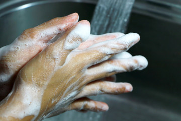 Cleaning the hands using liquid disinfectant soap under running water. close up. Personal hygiene, health care and Coronavirus prevention.