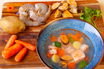 soup in a plate and ingredients included in it on a wooden board