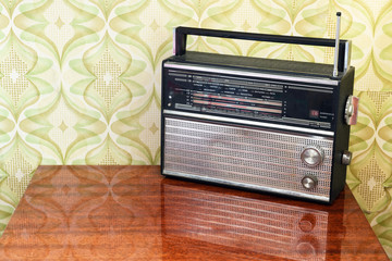 Retro radio on the table against the background of vintage wallpaper
