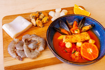 soup in a plate and ingredients included in it on a wooden board