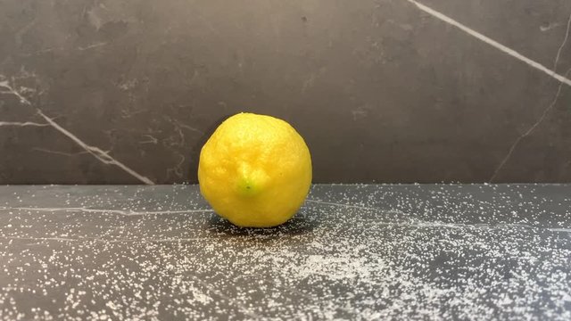 juego con un limón en superficie con azúcar  esparcida y rotando con una mano varios limones para que se muevan en redondo