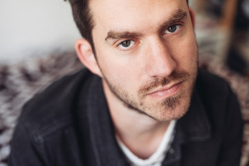 A close up portrait of a young handsome man looking serious, indoors