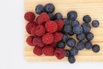 blueberries and raspberries in a wooden board