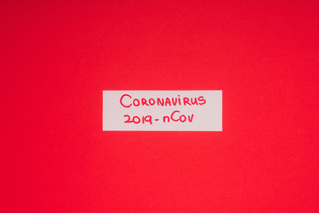 Top view of card with coronavirus 2019-nCov lettering isolated on red