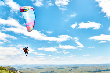 Salto en parapente desde el cerro con cielo azul y nubes de fondo, Cuchi Corral, Cordoba,...