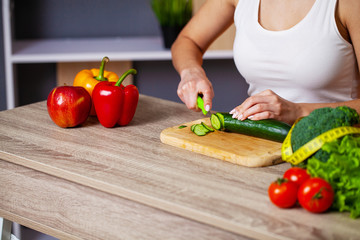 Closeup of woman slices cucumber for fresh salad