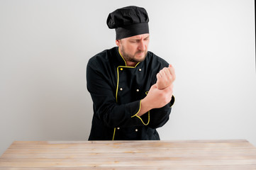 Young male chef in black uniform has wrist pain