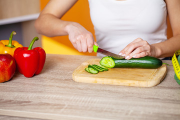 Closeup of woman slices cucumber for fresh salad