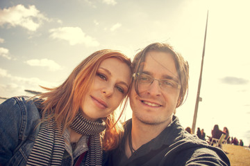 Happy young couple posing for selfie on a sunny day outside.