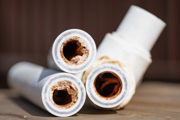 Old broken corroded plumbing pipes with red rust and limescale. Corrosion, sludge and hard water...