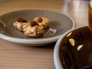 cookies with nuts are on a gray plate and a Cup of coffee are on a wooden table.