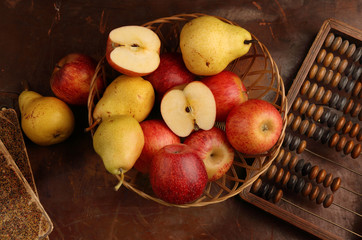 Apples, pears and old abacus on a brown background