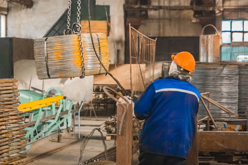 A working man in a reinforcement workshop controls equipment for moving metal structures