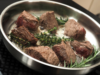 Organic beef fillet with rosemary and thyme in a stainless steel pan, view from above