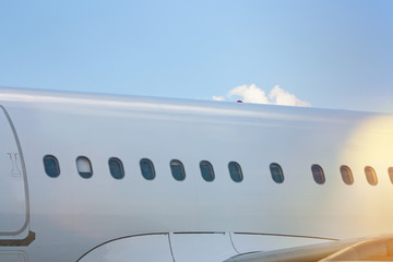 Close-up of the fuselage of a white passenger jet plane on a clear sunny day