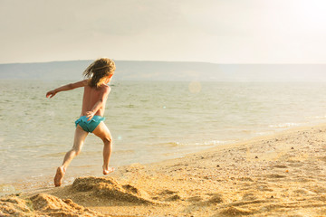 Fototapeta premium A girl runs along the sea along the surf line. Family vacation concept.
