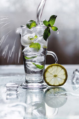 Cooling drink in a glass with lemon, ice and mint