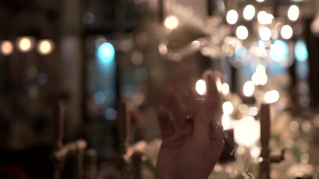 Bartender spinning a chrome bar spoon, ready to mix and to layer cocktail beverage at fancy restaurant. Skillful barman rotating long-handled spoon for alcoholic drinks in soft evening lighting.