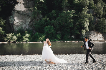 Wedding couple, groom and bride running, outdoor near river