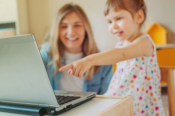 Happy daughter showing her mother something at the notebook