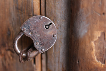 
Old rusty iron padlock on a wooden door