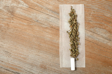 portion marijuana on paper for torsional filter on wooden table top view