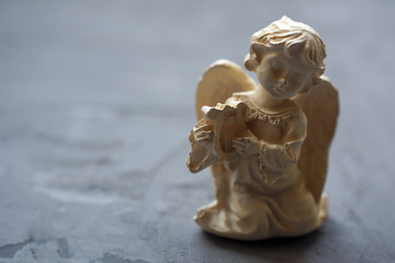 White little beautiful angel old ceramic figure with harp on a black background with copy space. Guardian angel, Valentine's Day, New Year concept