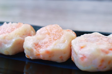steamed Chinese dumpling topping shrimp on black plate dipping soy sauce