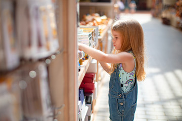 little girl chooses Souvenirs in street shop hotel