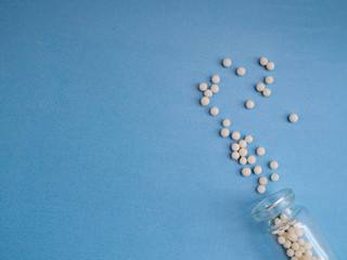 Homeopathic globules and glass bottle on blue background. Homeopathic Medicine