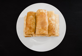 tasty pancakes with cottage cheese in a white plate isolated on a black background.
