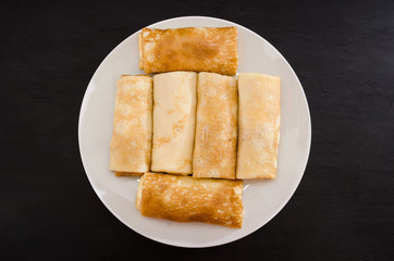 tasty pancakes with cottage cheese in a white plate isolated on a black background.