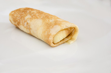 pancake with curd rolled into a roll in a white plate. Close-up.