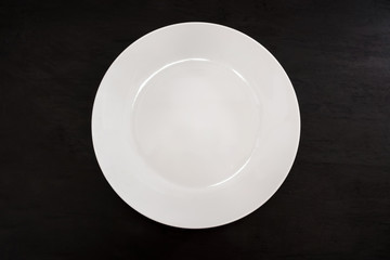white plate isolated on a black background. View from above. Empty plate.