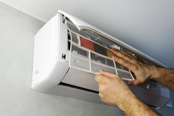 maintenance of air conditioner split system. man's hand holds inner filter from air conditioner, cleaning from allergen, dust and dirt for healthy living
