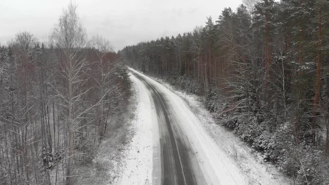 Bird's-eye view of the road in an idyllic winter landscape, new year's picture with an empty winter highway in a dense forest wrapped in snow