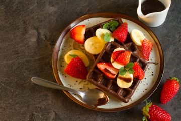 Chocolate waffles with milk , bananans and berries for breakfast