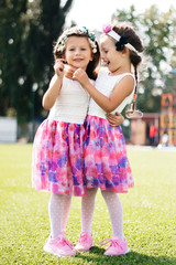 two twin girls hugging on the grass happy and laughing